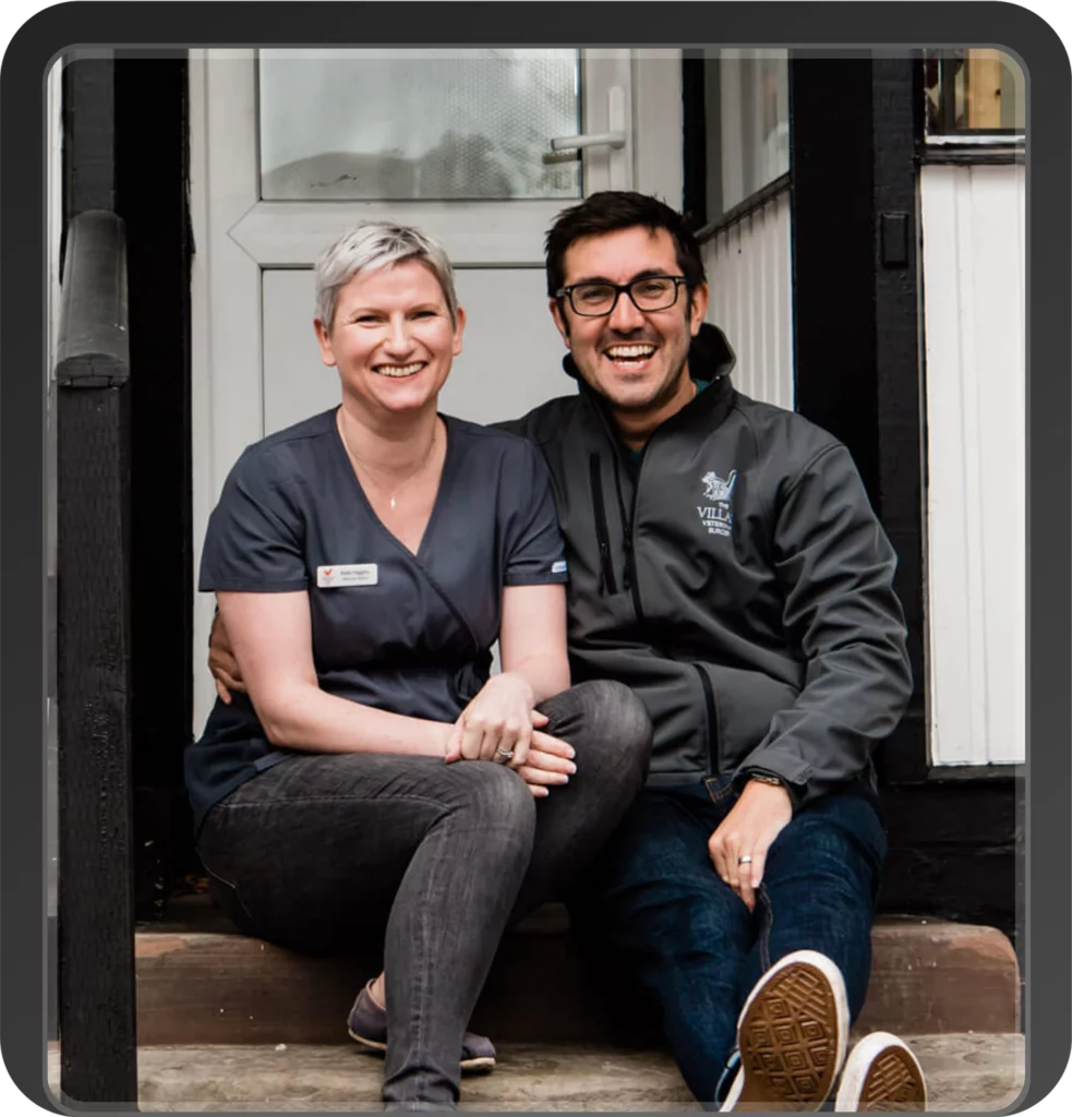 Two veterinary team members smiling on clinic steps.